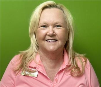 Female employee smiling in front of a green wall.