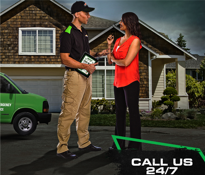 servpro tech standing with client outside of house